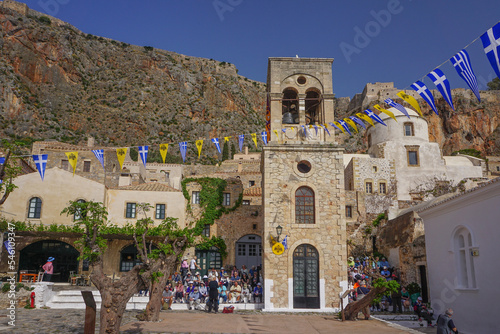 Monemvasia, Greece: Tourists on the steps of the main square, under Greek and Byzantine pennants, in the medieval fortress town founded in 583 AD.