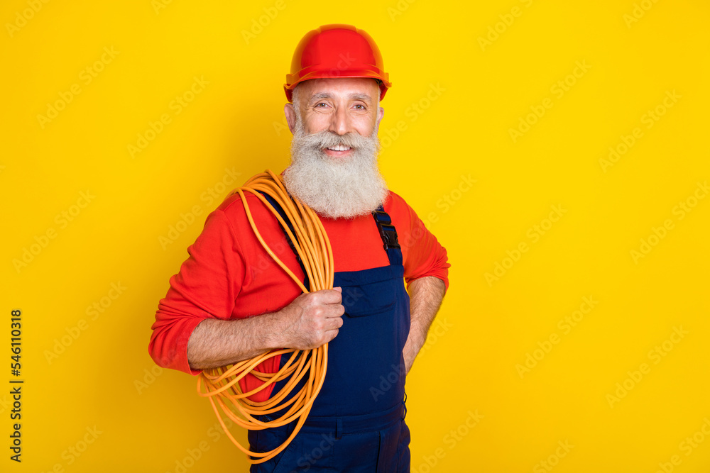 Photo portrait of nice grandparent repair hold shoulder cord coil toothy smile dressed safety uniform isolated on yellow color background