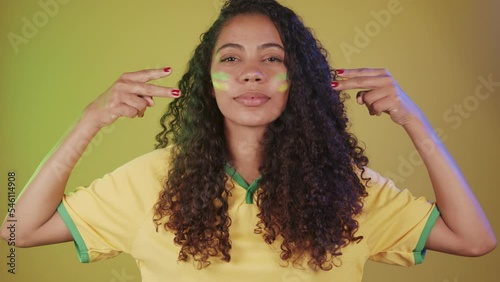 Black woman, soccer fan from Brazil, putting paint on her face.