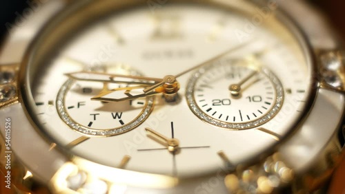 Clock hands in motion on the dial clock face of a gilded gold plated mechanical quartz glamorous chronometer watch close-up macro. Running of time and life 