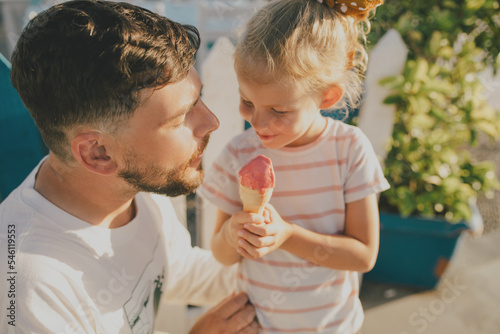 Father and his little daughter eating ice cream and having fun outdoors.