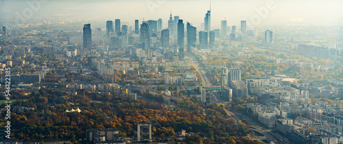 Aerial view of city centre of Warsaw with shillouettes of high rise buildings and skyscrapers. Autumn trees. Foggy grey cityscape. Horizontal shot. High quality photo