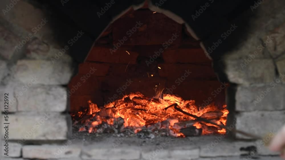 Glowing hot red coal in brick oven sparks while being pushed Glowing hot red coal in brick oven sparks while being pushed