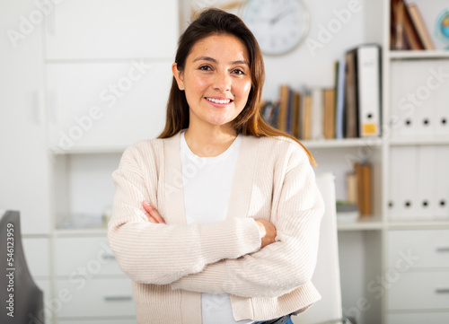 Portrait of a smiling female manager in a well-lit office. Close-up portrait
