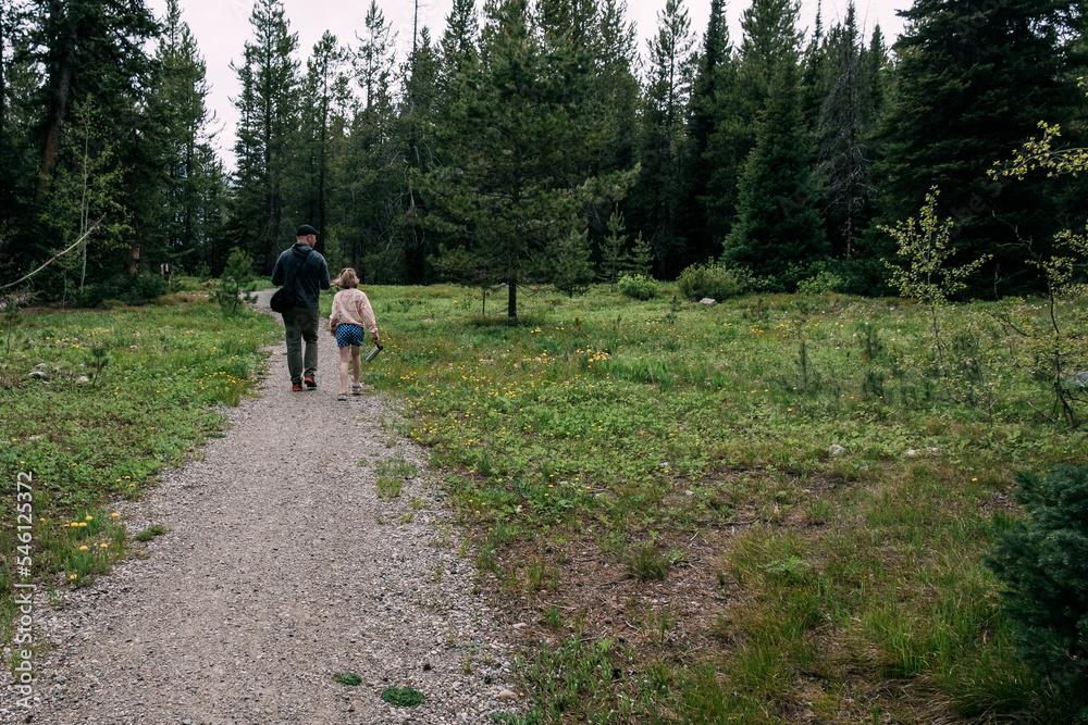 Father and daughter walking on hiking trail in forest Father and daughter walking on hiking trail in forest