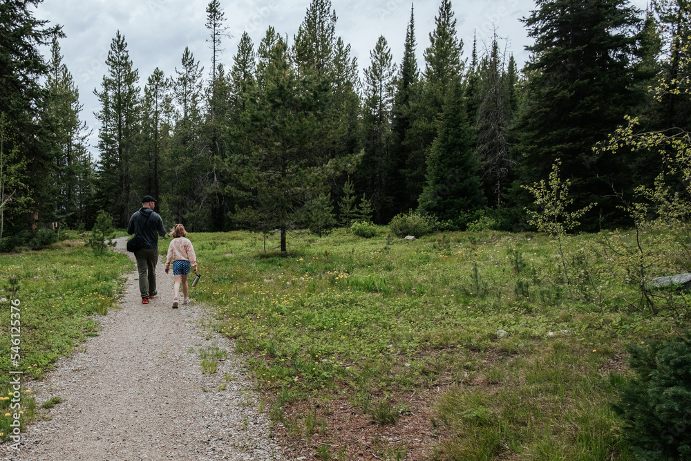 Father and daughter walking down hiking trail in forest
