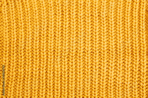 Knitted wool background of yellow or saffron color. Top view.