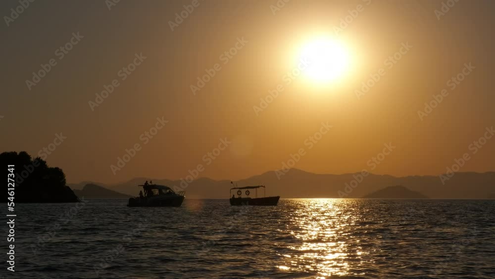 Silhouette of sunset over alone sailboat. A view of sailboats stay in the sea during orange sunset. A concept of romantic time by the sea in summer. Silhouette of sunset over alone sailboat. A view of sailboats stay in the sea during orange sunset. A concept of romantic time by the sea in summer.