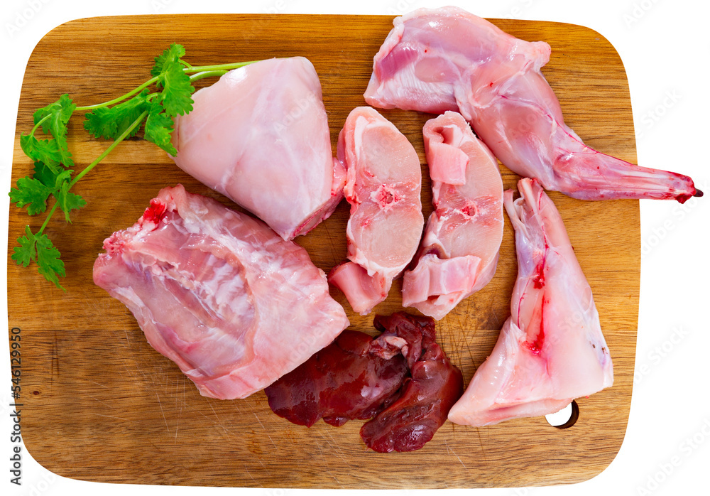 Raw sliced rabbit lying on wooden cutting board with seasonings. Dietary cooking ingredient. Isolated over white background