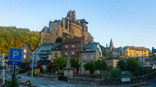 Scenic view of medieval fortified stone castle dominating residential buildings in small French town of Estaing in Aveyron department on summer day