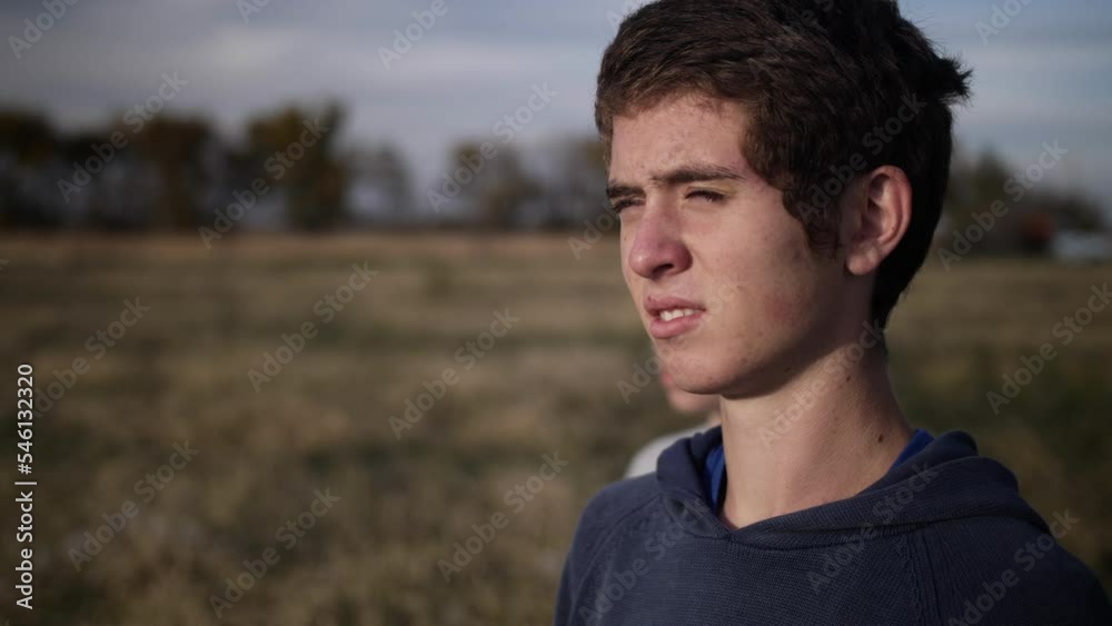 Two teen boys - friends - standing together with light on their face as they watch the sun set. Two teen boys - friends - standing together with light on their face as they watch the sun set.