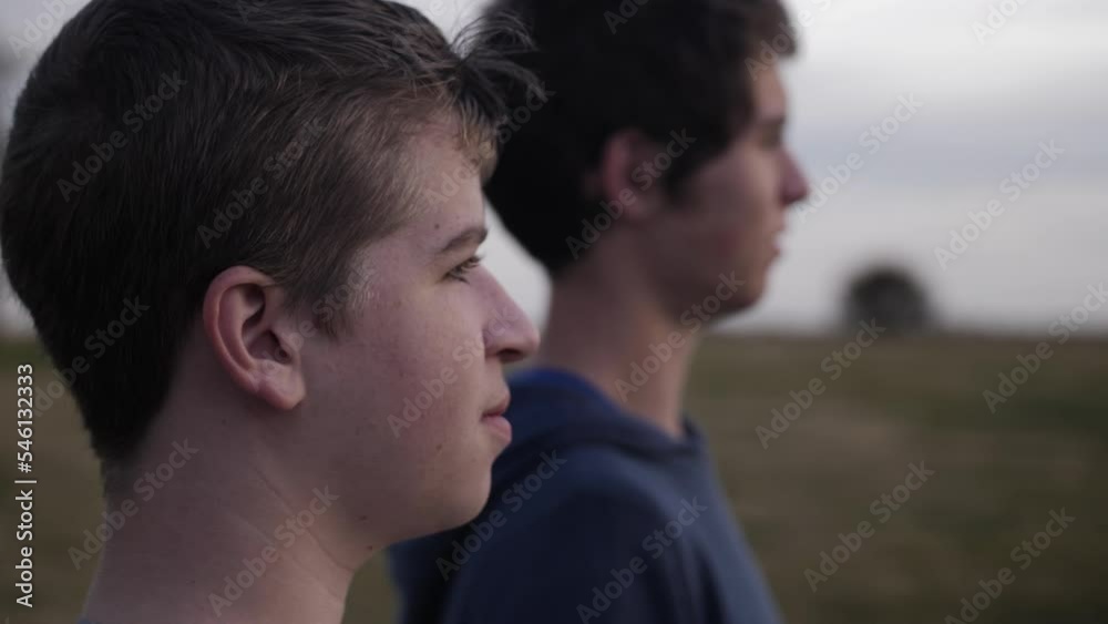 Two happy boys - friends - together standing together watching the sun setting in a field. Two happy boys - friends - together standing together watching the sun setting in a field.