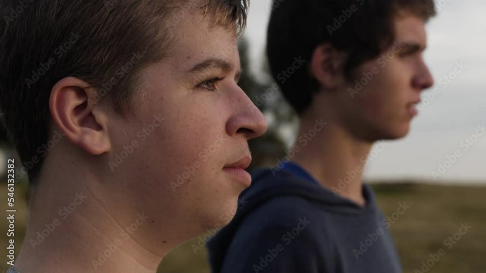 Two teenager boys (friends) together watching the sunset in a field. Two teenager boys (friends) together watching the sunset in a field.
