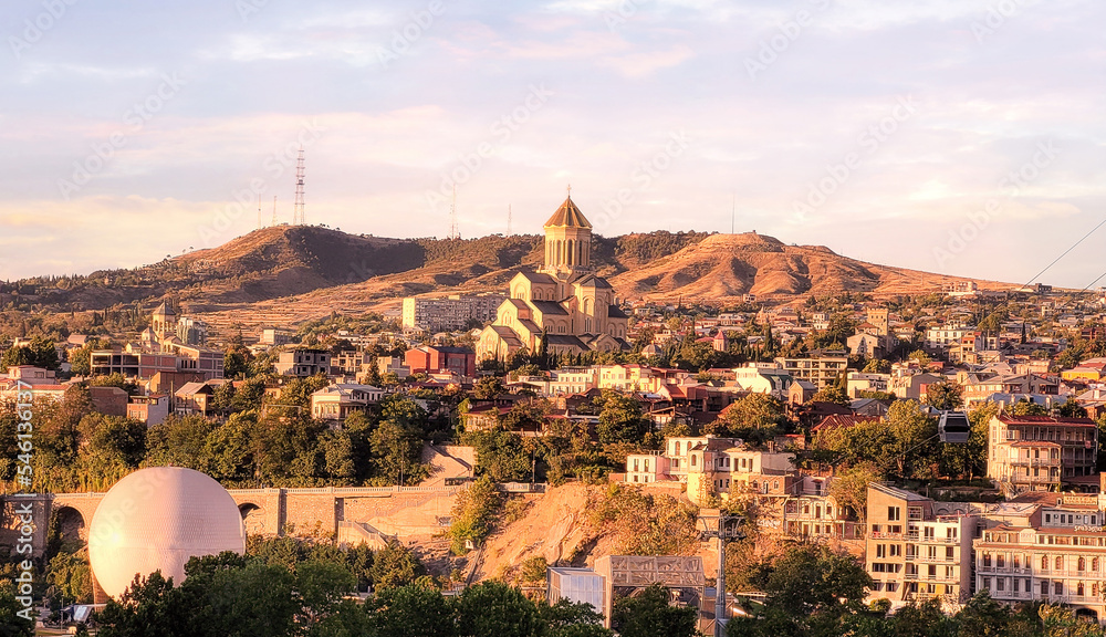 Summer sunset view of the city of Tbilisi Tiflis the capital of Georgia with Holy Trinity Cathedral commonly known as Sameba, the main cathedral of the Georgian Orthodox Church located on Elia Hill