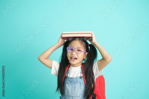 Portrait of happy lazy little girl covering head with book and smiling to camera.