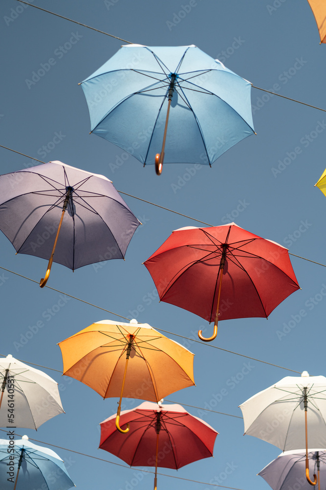 Obraz premium Colorful umbrellas fixed on steel ropes between buildings against blue sky. Famous Umbrella street in center of old city of Antalya, Turkey. 
