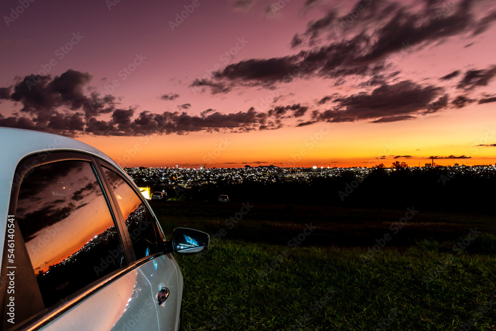 Parked car in sunset time with lights of the city backround in Brazil