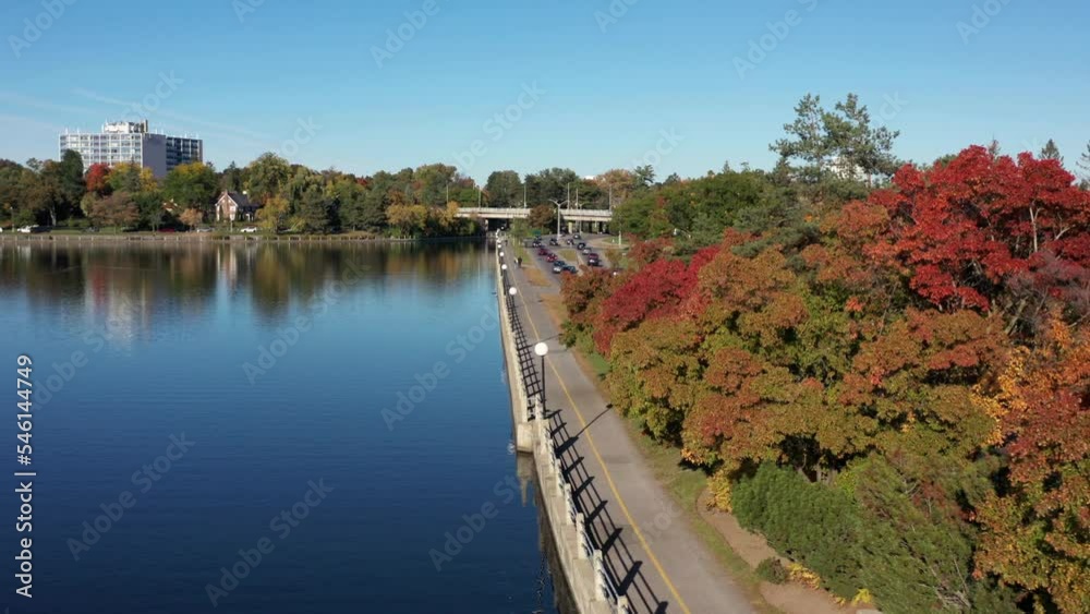 Drone shot along Rideau Canal in Ottawa Ontario Canada in fall season with reflections off water beside Colonel By drive with traffic flowing Drone shot along Rideau Canal in Ottawa Ontario Canada in fall season with reflections off water beside Colonel By drive with traffic flowing