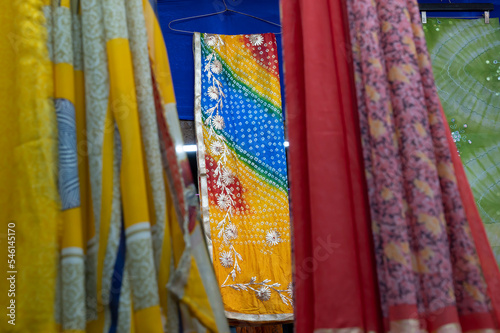 Rajasthani womens clothes are hanging for sale , being displayed in a shop at famous Sardar Market and Ghanta ghar Clock tower in the evening.