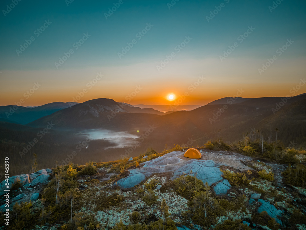 a sunrise over a camping tent on a mountain, with fog