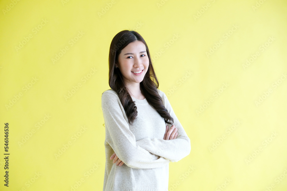 Happy asian woman smiling, arm cross and looking at camera while standing over isolated yellow background, Portrait of asia female Happy asian woman smiling, arm cross and looking at camera while standing over isolated yellow background, Portrait of asia female