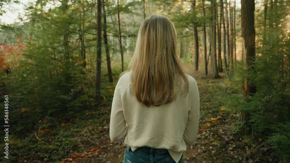 White shirt blond girl walking though the forest during sunset White shirt blond girl walking though the forest during sunset