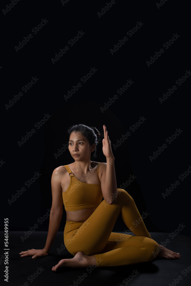 asian woman doing  practicing yoga on yoga mat isolated on black ,studio lighting
