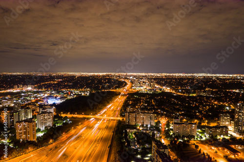 Top view of car traffic at intersection lane and buildings. Long exposure of urban cityscape at night. Modern city in Canada full of night lights from energy and power. © desertsands