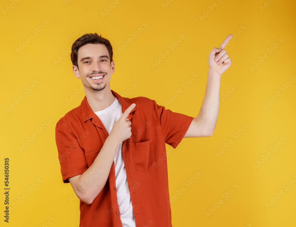 Portrait of young man pointing fingers at copy space isolated on yellow studio background Portrait of young man pointing fingers at copy space isolated on yellow studio background