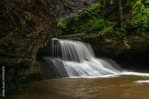 Fototapeta Naklejka Na Ścianę i Meble -  Waterfalls under rock overhang in lush green forest 