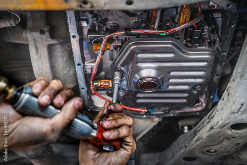 Auto mechanic installing an automatic transmission filter.	 photo