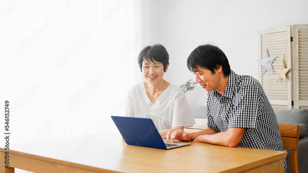 ノートパソコンを一緒に見るミドル男性とミドル女性