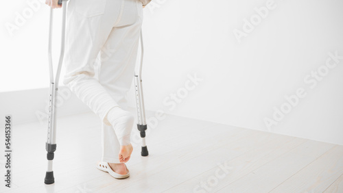 松葉杖をついて歩くミドル女性　リハビリイメージ
