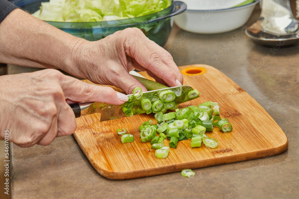 Chef cuts leek on wooden board in the kitchen Chef cuts leek on wooden board in the kitchen