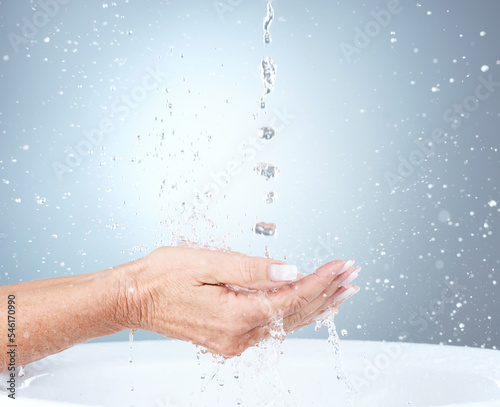 Water splash, studio and woman cleaning hands in sink or basin on blue background with mockup. Hygiene, health and mature female model washing hands for wellness, skincare and safety from bacteria.