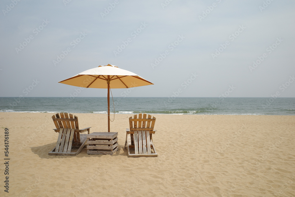 Fototapeta premium Beach Wooden chairs and a parasol on sand beach for looking sea view .vacation on the beach 