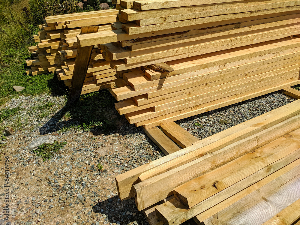 Wooden boards stacked in rows and lie on the ground. Boards for construction are sawn with bars. Close-up Wooden boards stacked in rows and lie on the ground. Boards for construction are sawn with bars. Close-up