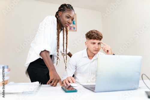 due giovani ragazzi multirazziali riflettono su un progetto in ufficio utilizzando il computer photo