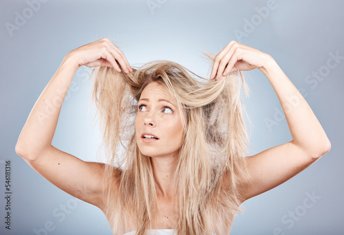Hair care, stress and woman sad about frizz, split ends and messy style against a grey studio background. Frustrated, unhappy and angry model with problem with her hair, frustration and worry