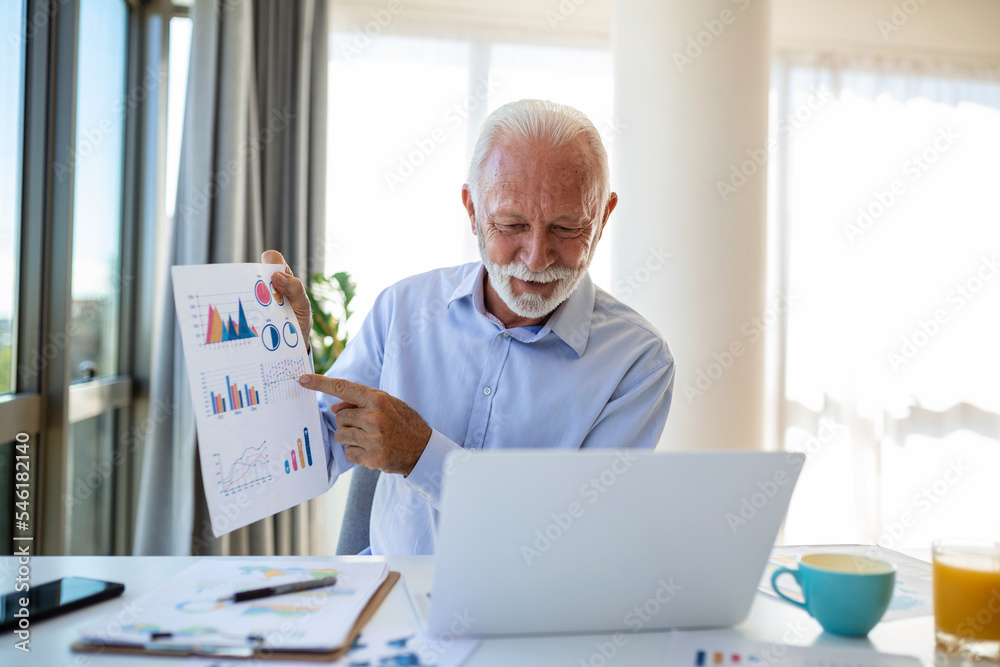Focused senior business man presenting charts and graphs on video call online. Mature business man having conference call with client on laptop explaining how business work