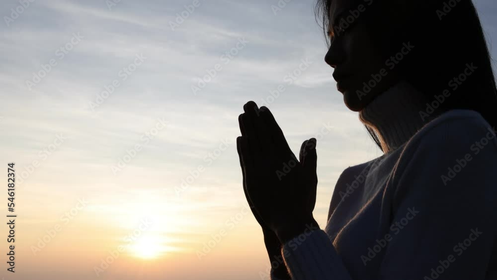 Silhouette of a women is praying to God on the mountain. Praying hands ...