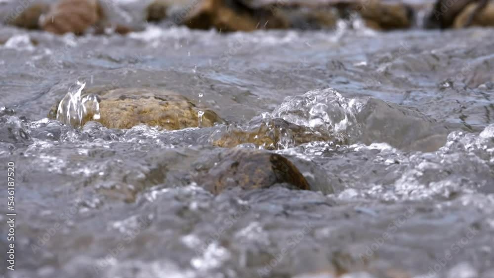 Clear stream running through stone boulders Abundant river flowing in slow motion. Wild mountain river water splashing in summer near the river bank environment. Clear stream running through stone boulders Abundant river flowing in slow motion. Wild mountain river water splashing in summer near the river bank environment.