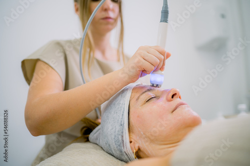 Female cosmetologist massaging forehead of woman