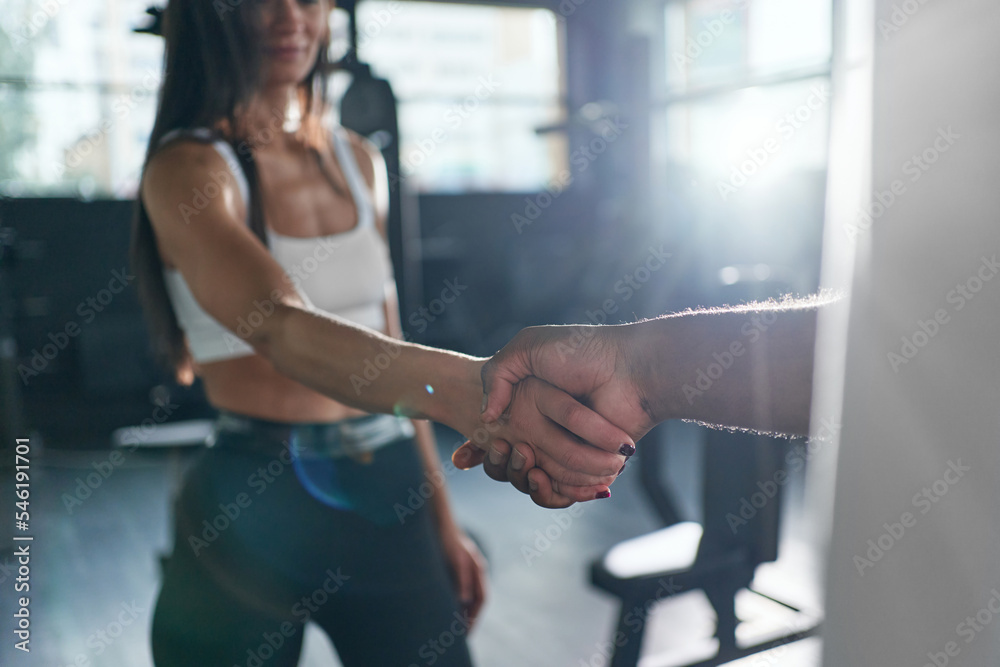 trainer and fitness woman shaking hands with each other.