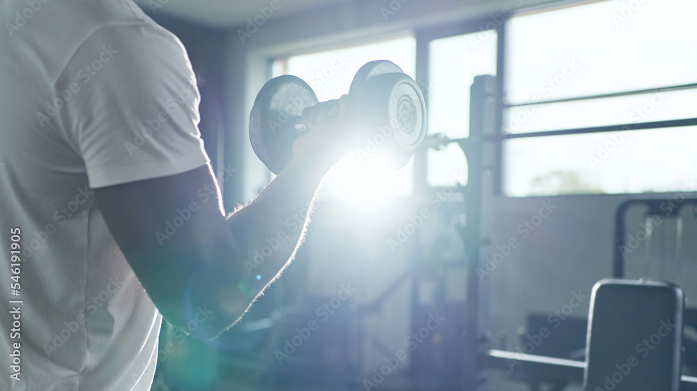 coach bodybuilder performing an exercise with dumbbells.