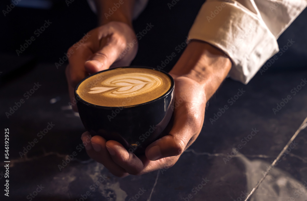 Coffee Barista man holding cup of coffee latte art in coffeeshop, barista concept