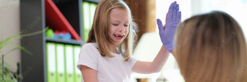 Obraz premium Happy cute baby girl high five to female pediatrician doctor