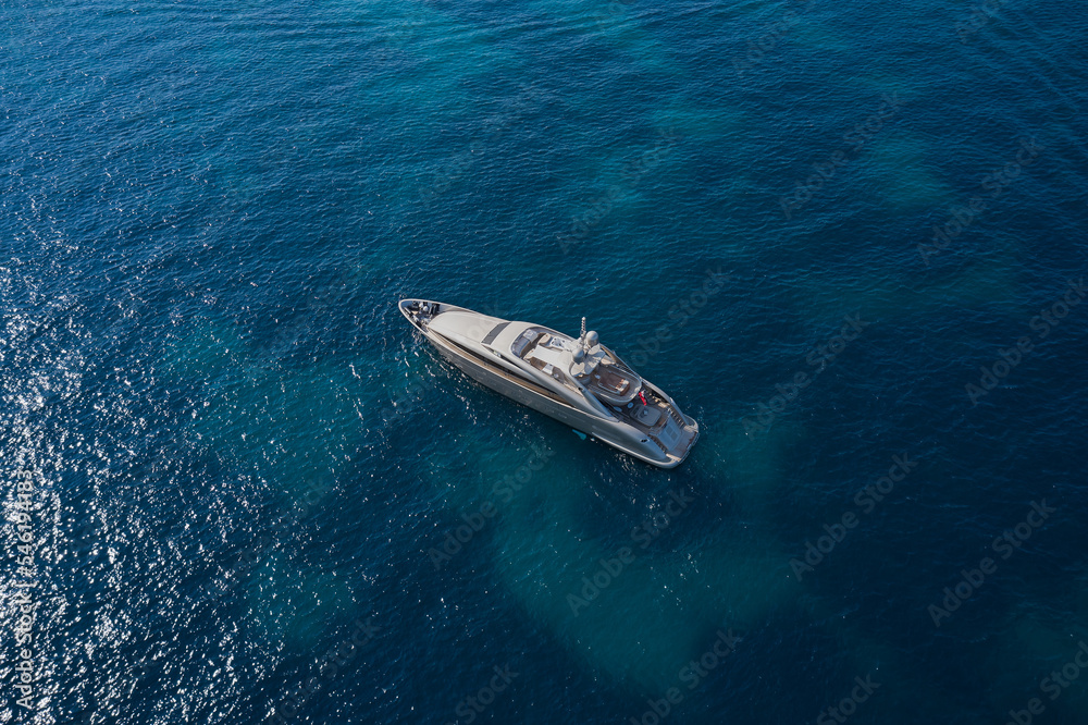 A large Mega yacht for travel is anchored on clear water. Top view. Innovative yachts on the water vice air.