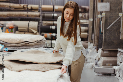 Fotografie Woman touching soft fluffy carpet in hardware store, home furniture buying conce