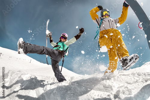 Happy couple of snowboarders are having fun and jumps with snowboards in hands. Winter holidays at ski resort